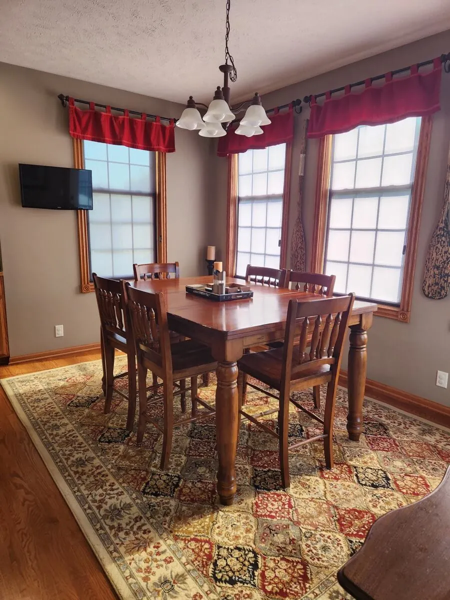 Dining room with a wood table, six chairs, and a patterned rug, dusted and vacuumed